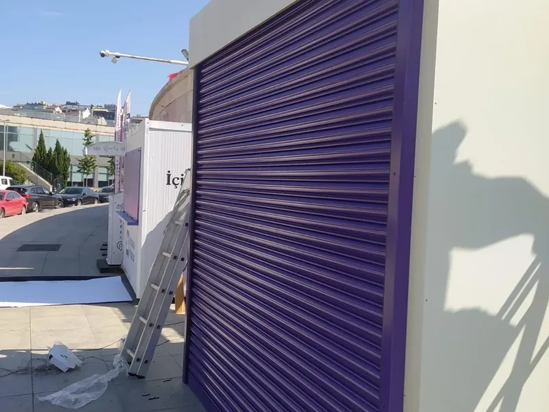 Mor renge boyanmış kepenk perdesi, yanında montaj merdiveni